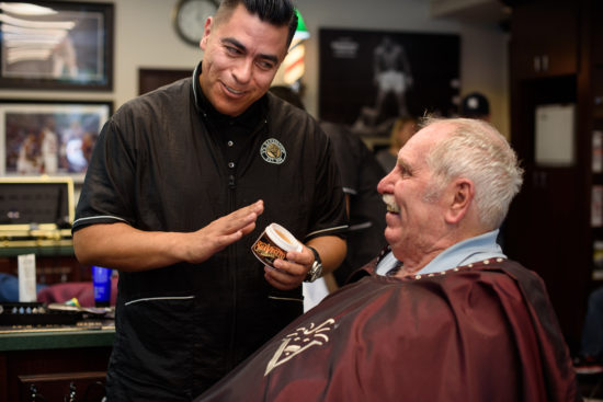 Barber showing a hair pomade to a patron and laughing